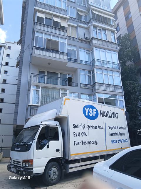 Apartman önünde YSF Nakliyat yazılı kapalı kasalı kamyon.