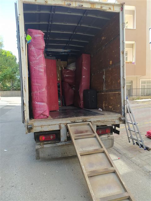 Arka kapısı açık kamyonda yüklenmiş ambalajlı eşyalar.